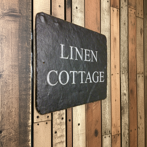 Slate sign with 'Linen Cottage' text on a wooden surface