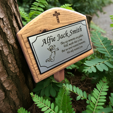 Wooden plaque with engraved text and design, attached to a tree