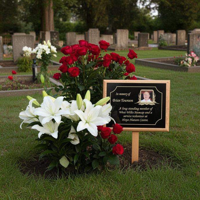 Floral arrangement with red and white flowers and a memorial plaque in a cemetery.