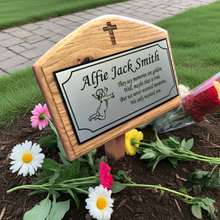 Memorial plaque with engraved text and flowers on a grave