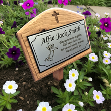 Memorial plaque with engraved text and cross design, set against a garden background with flowers.