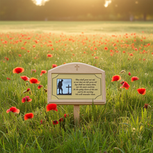 Memorial sign with a silhouette of a soldier and cross in a field of red poppies.