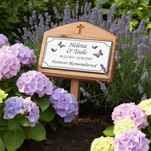 Memorial sign for Helena Hélèna ×ötöle surrounded by flowers in a garden setting