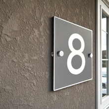 Modern house number '8' on a textured wall