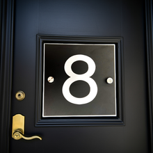 Black door with gold handle and white number 8