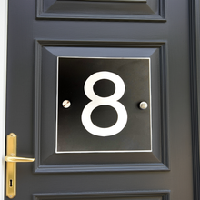Black door with gold handle and white house number '8'