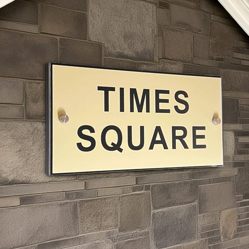 Gold sign with 'TIMES SQUARE' text on a brick wall