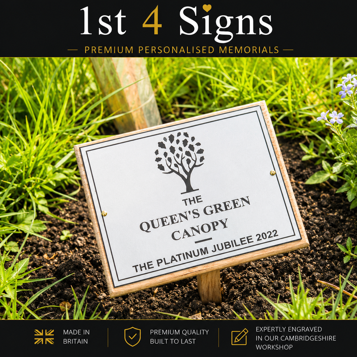 A custom wooden garden memorial plaque with a white engraved face and black text, reading 'THE QUEEN'S GREEN CANOPY THE PLATINUM JUBILEE 2022', planted in dark soil with green grass around it. A black banner at the top reads '1st 4 Signs Premium Personalised Memorials', and a black footer strip at the bottom highlights 'Made in Britain', 'Premium Quality Built to Last', and 'Expertly Engraved in our Cambridgeshire Workshop'.