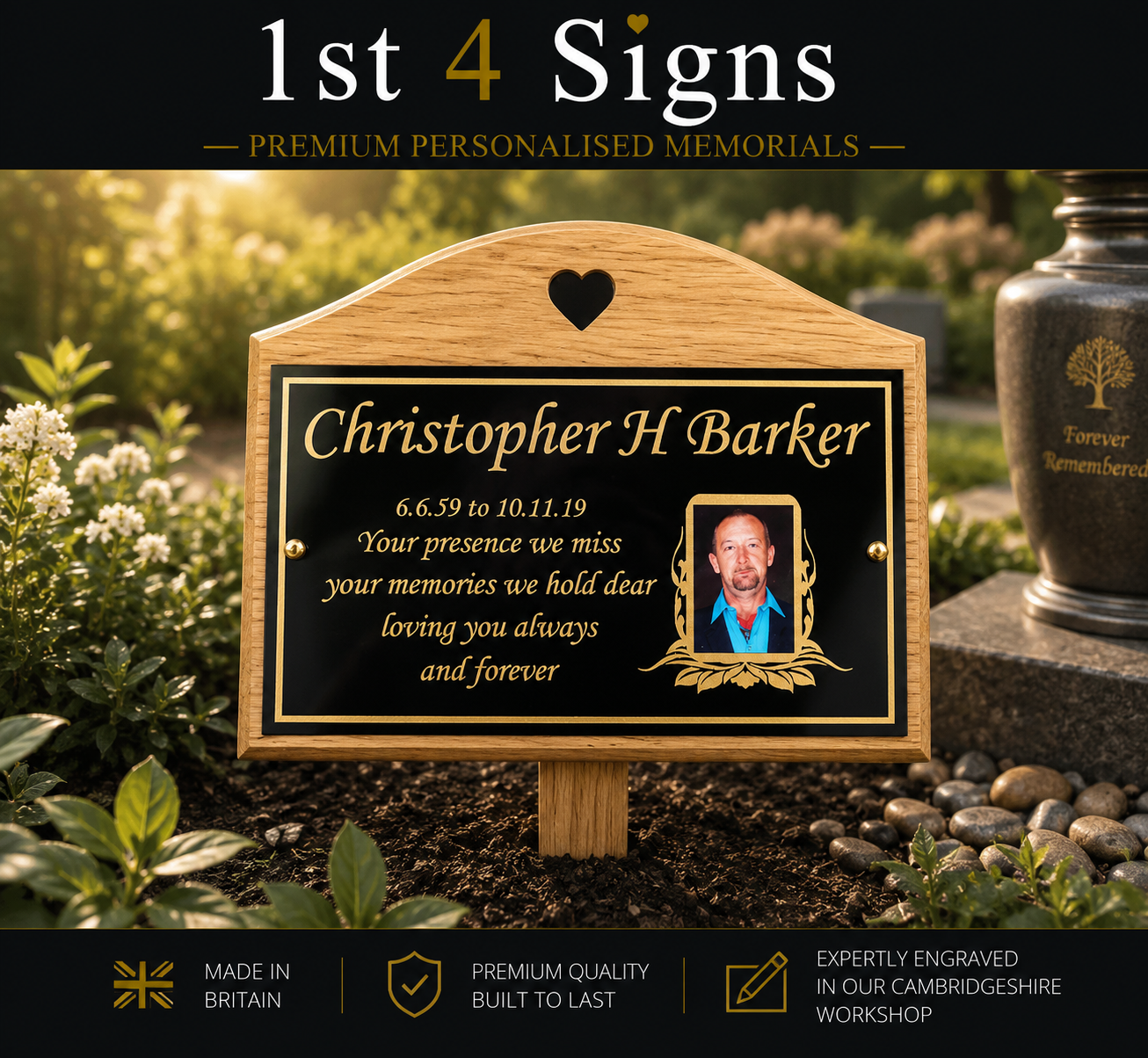 Personalized wooden memorial plaque with a black engraved center panel, shown outdoors in a garden setting. The plaque is engraved with the name 'Christopher H Barker', dates, a heart icon, and a small portrait photo.