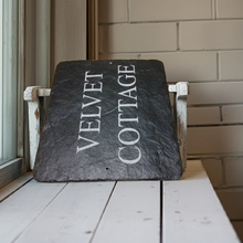Slate sign with 'Velvet Cottage' on a wooden surface