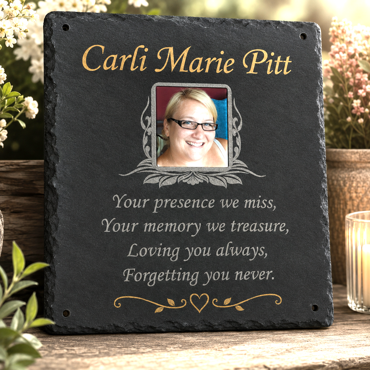 Personalized black slate memorial plaque with gold and white text, a photo frame insert, and a floral tabletop setting.