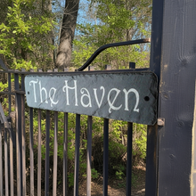 Metal gate with 'The Haven' sign in a forest setting