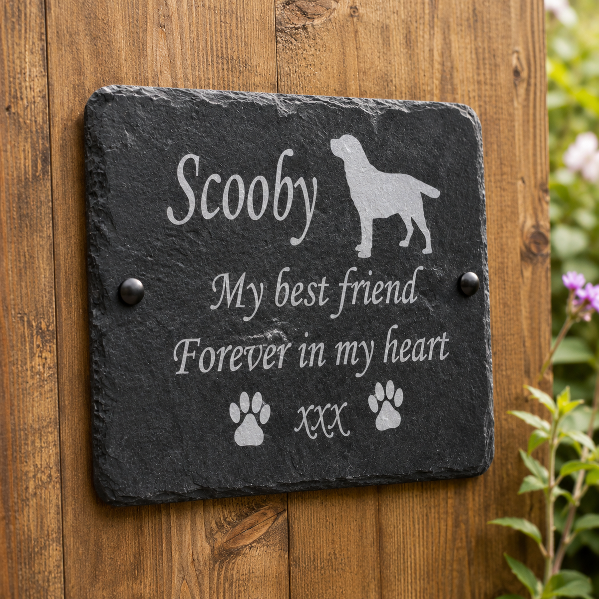 Personalized black slate memorial plaque mounted on a wooden wall, engraved with the name 'Scooby', a dog silhouette, the phrase 'My best friend Forever in my heart', and paw prints.