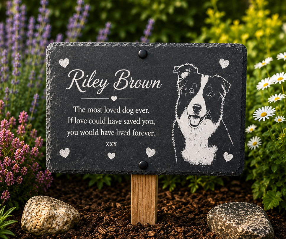 Personalized pet memorial garden plaque on a wooden stake, featuring a black slate board with white engraved text and a dog portrait, displayed in a garden setting.