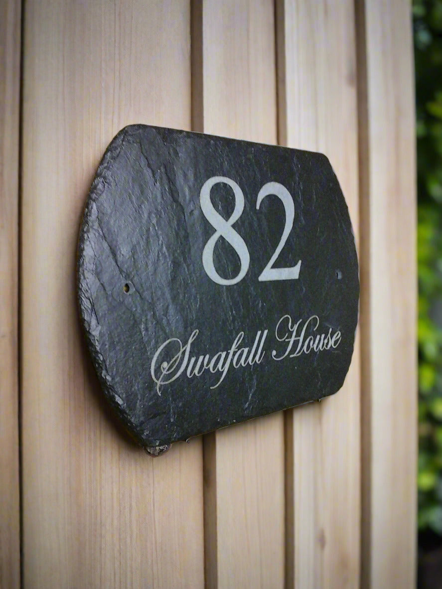 Slate house number sign with '82' and 'Swafall House' on a wooden fence