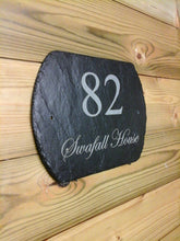 Slate house number sign with '82' and 'Swafall House' on a wooden fence