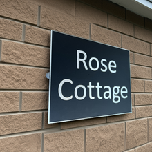 Sign reading 'Rose Cottage' on a brick wall
