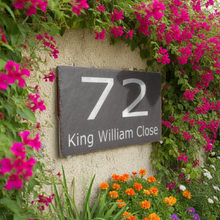 House number sign '72 King William Close' on a wall with flowers