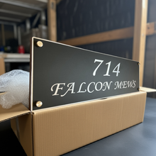 Address sign with '714 Falcon Mews' on a cardboard box in an indoor setting