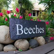 Slate sign with 'Beeches' text in a garden setting with pink tulips and rocks.