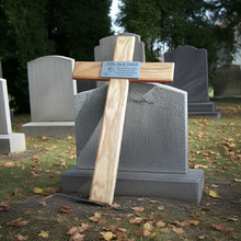 Wooden cross with a plaque on a gravestone in a cemetery