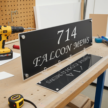 Black signs with white text on a workbench with tools in the background