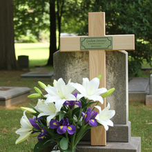 Grave with wooden cross and floral arrangement in a cemetery