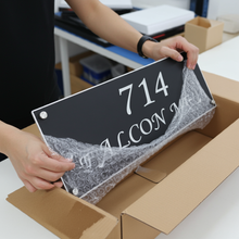 Person unpacking a house number sign from a box