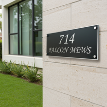 House number sign on a building exterior with '714 Falcon Mews' text.