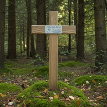 Wooden cross with a plaque in a forest setting