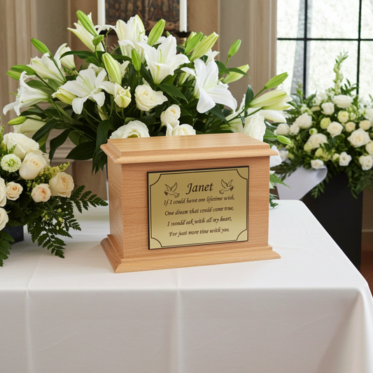 Wooden urn with engraved text on a table with floral arrangements in the background