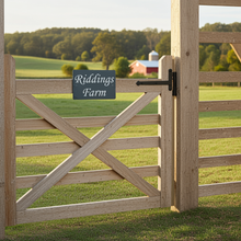 Wooden gate with 'Riddings Farm' sign in a rural landscape