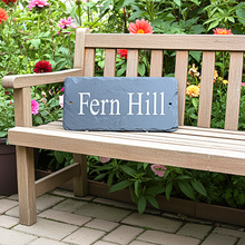 Wooden bench with a slate sign reading 'Fern Hill' in a garden setting.