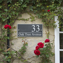 House number sign '33' on a stone wall with ivy and red roses