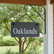 Decorative sign with 'Oaklands' text hanging outdoors against a garden background