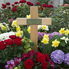 Wooden cross with a plaque in a garden with colorful flowers