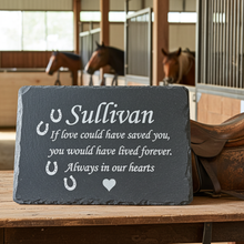 Slate plaque with engraved text in a stable setting with horses in the background