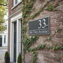 House number sign on a brick wall with ivy, featuring '33 Oak Tree Avenue'.