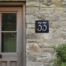 House number '33' on a stone wall next to a wooden door.