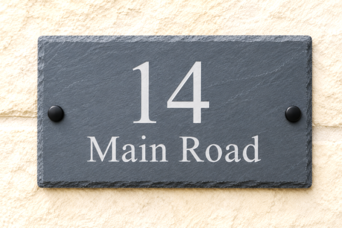A rectangular dark slate house number plaque reading '14 Main Road' in white lettering, mounted on a light beige textured wall.