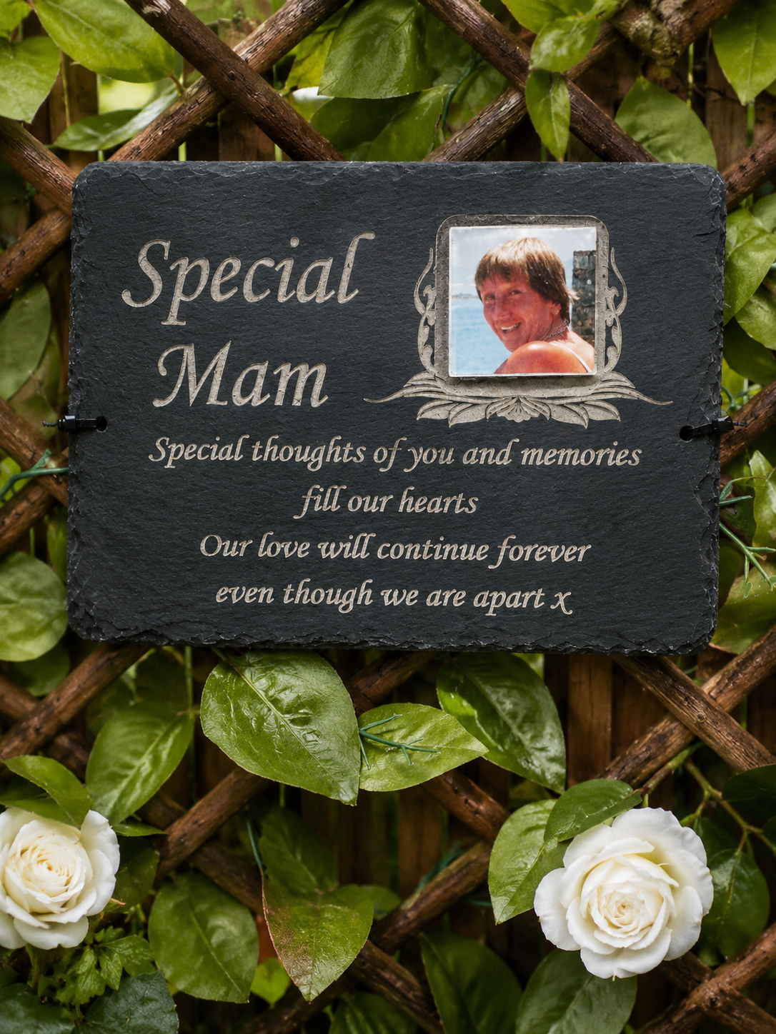 Personalized dark slate memorial plaque for 'Special Mam' with a photo frame insert and engraved text, displayed against a wooden trellis and green foliage background with white roses.