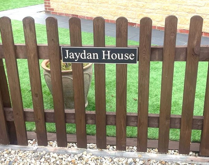 Personalised black aluminium house sign with white lettering, contemporary matt metal house plaque available in multiple sizes with hidden floating or stainless steel stand-off fixing options for homes and businesses.