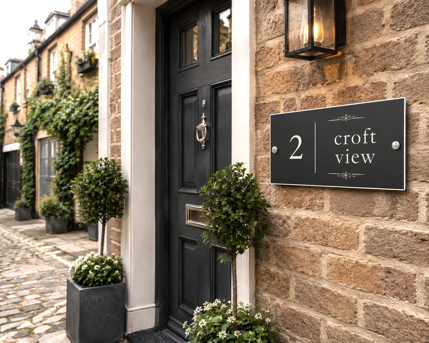 A black rectangular house number 2 sign with the words 'croft view' in white, mounted on a rustic stone wall next to a black front door with a wall-mounted lantern light.