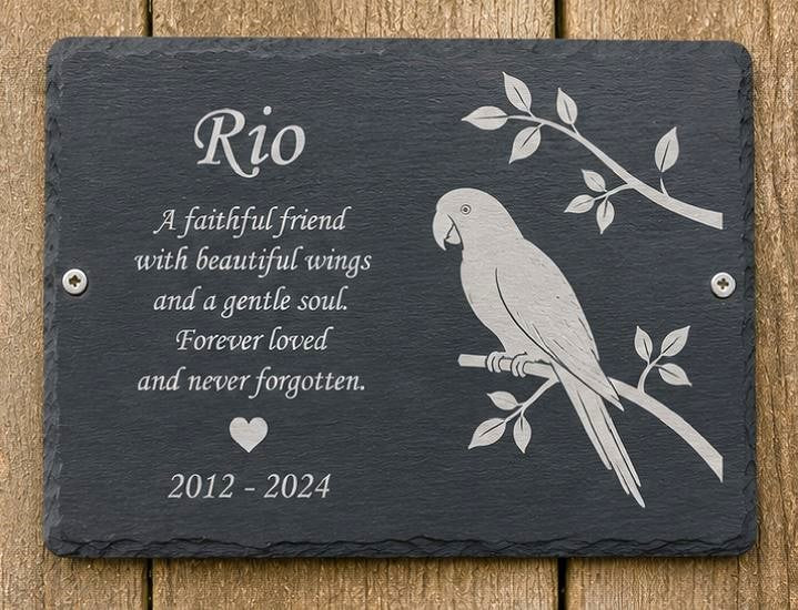 Slate plaque with engraved parrot design and text on a wooden background