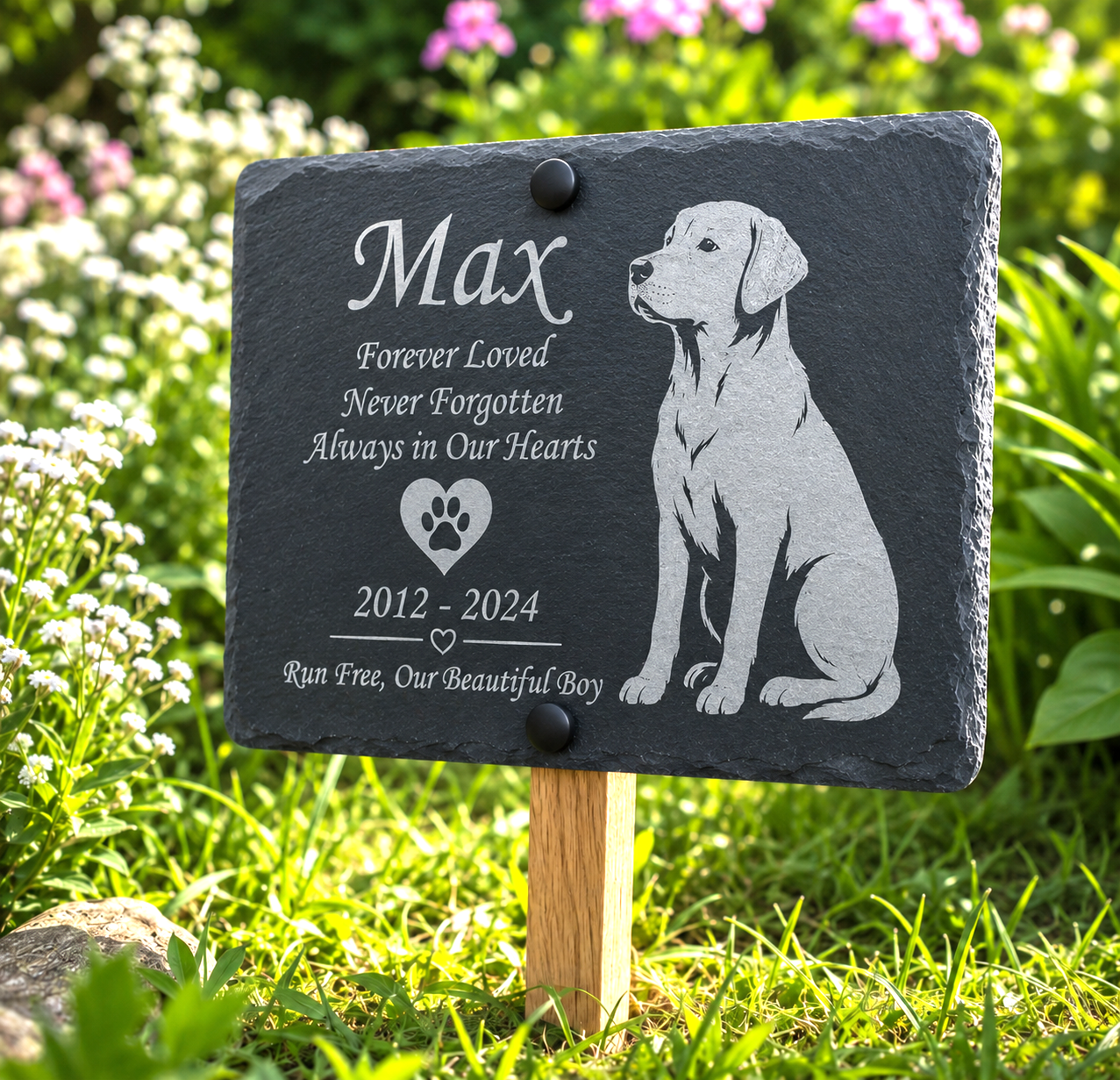 Personalized black slate pet memorial garden plaque engraved with the name Max, a puppy illustration, and remembrance text, mounted on a wooden stake in a grassy garden with flowers.