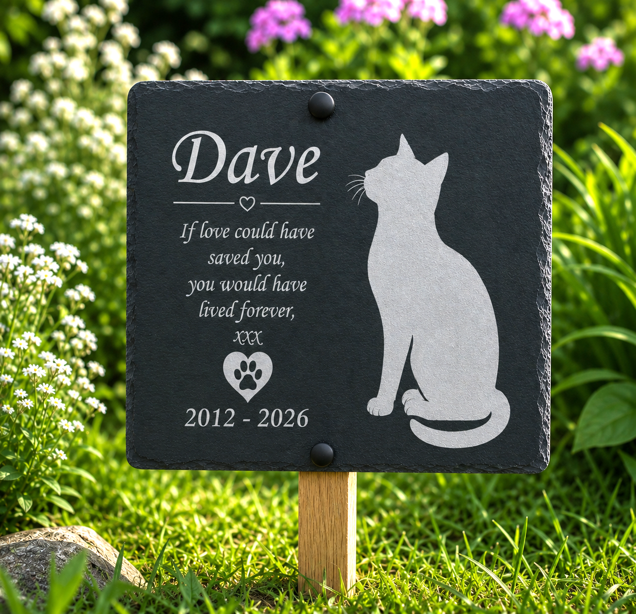Personalized black slate garden memorial plaque on a wooden stake, featuring an engraved cat silhouette and remembrance text for 'Dave', set in a grassy garden with white and pink flowers.