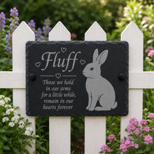 Slate plaque with rabbit illustration and text on a white picket fence with flowers in the background