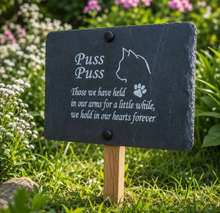 Slate pet memorial with text and paw print on a grassy background