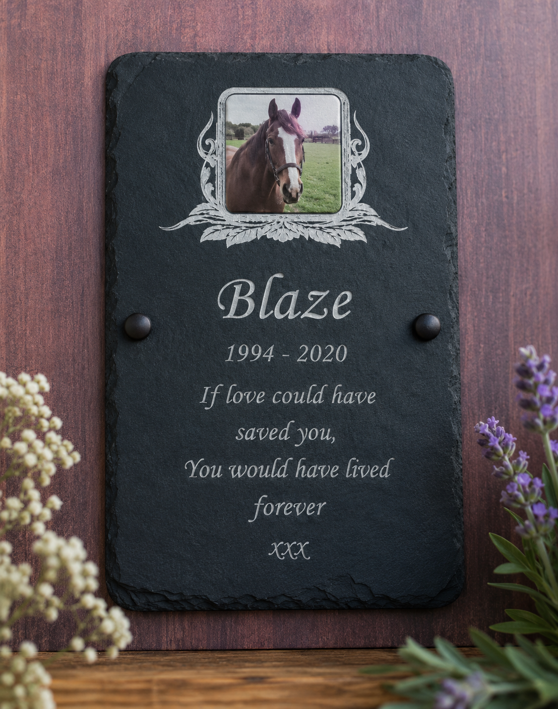 Personalized black slate memorial plaque with a photo of a horse, engraved text, and decorative silver border details, displayed on a wooden surface with flowers at the sides.