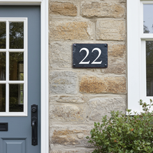 House number '22' on a stone wall next to a blue door.